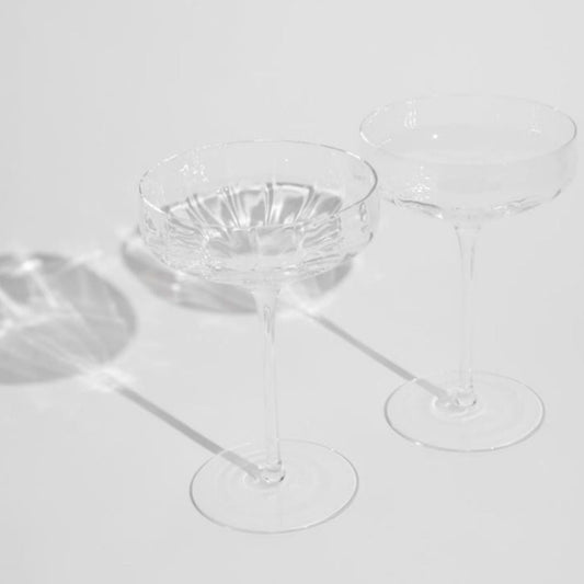 Clear coupe glass cocktail glasses on a light gray background