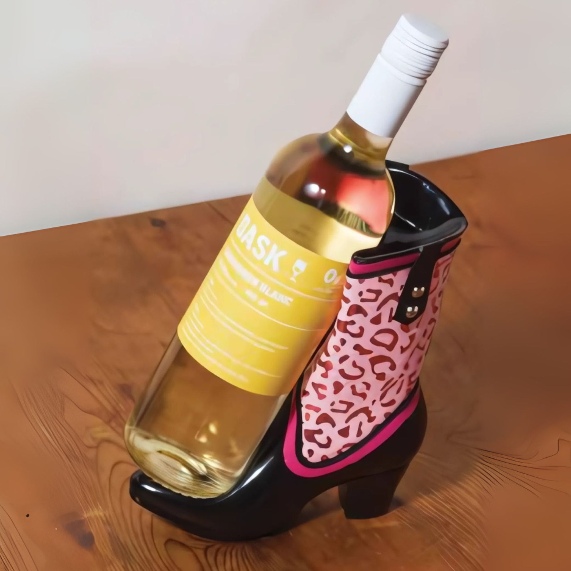 Wine bottle in a pink and black high-heeled shoe holder on a wooden surface