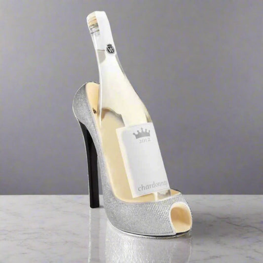 Bottle of white wine inside a high-heeled shoe on a gray background