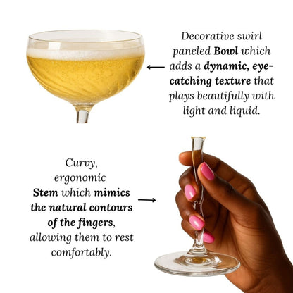 Cocktail glass with decorative swirl panelled bowl and curvy stem, held by a hand.