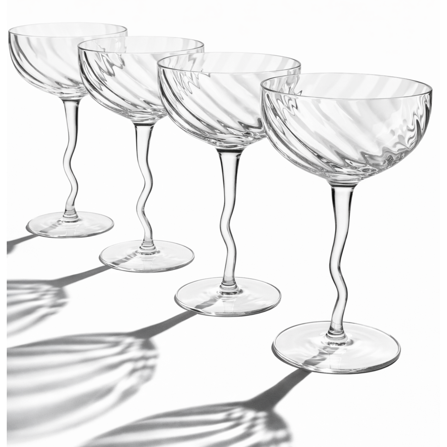 Set of four clear glass cocktail glasses with wavy design on a white background